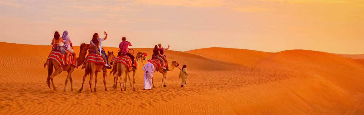 family of people riding on camels in the desert