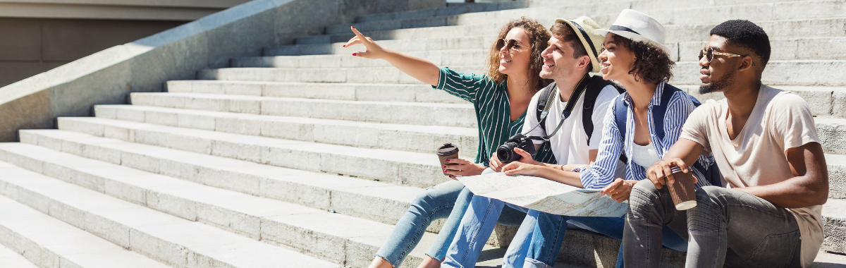 Gen X travelers sitting on some stairs pointing at something 