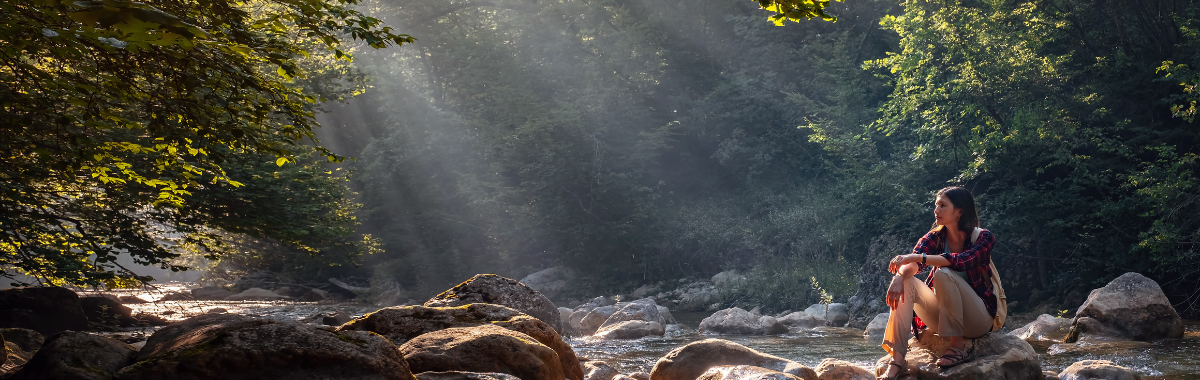 woman sitting on a rock near a river