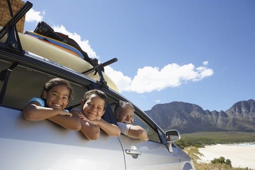 family in car on road trip to the beach