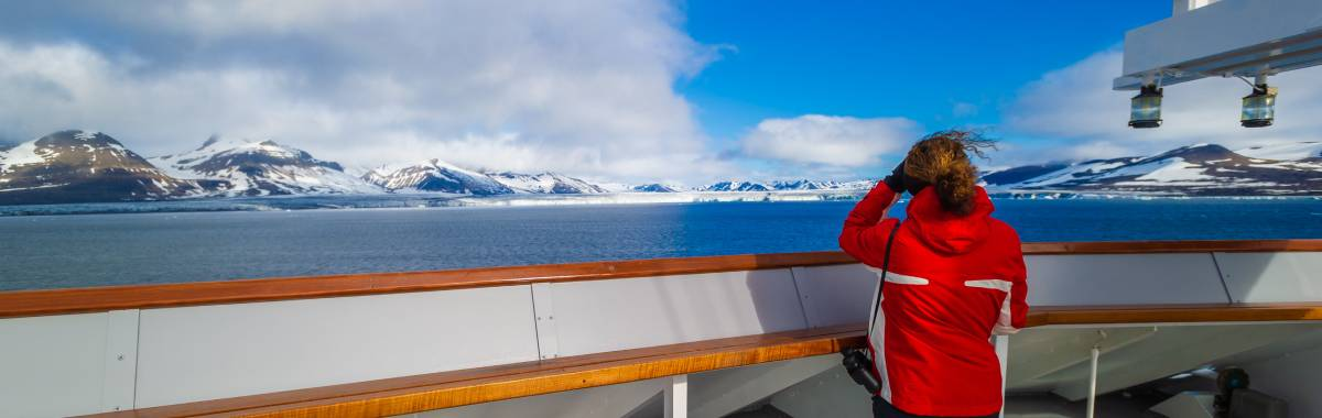 woman on a ship with a red coat looking at the glaciers