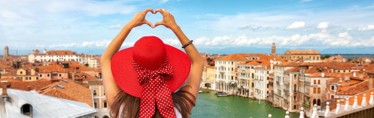 lady in a red hat making a heart hand to venice