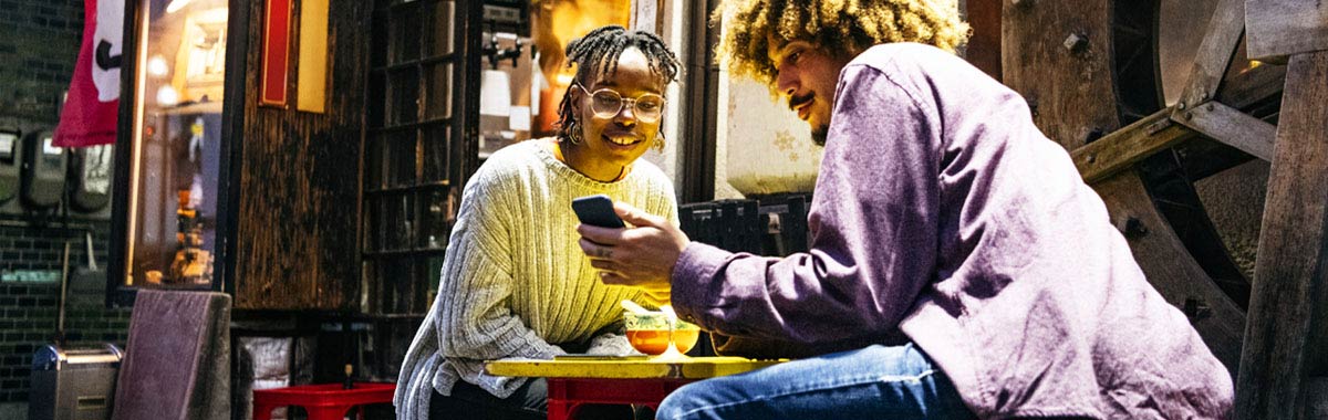 couple sitting outside japanese restaurant looking at phone