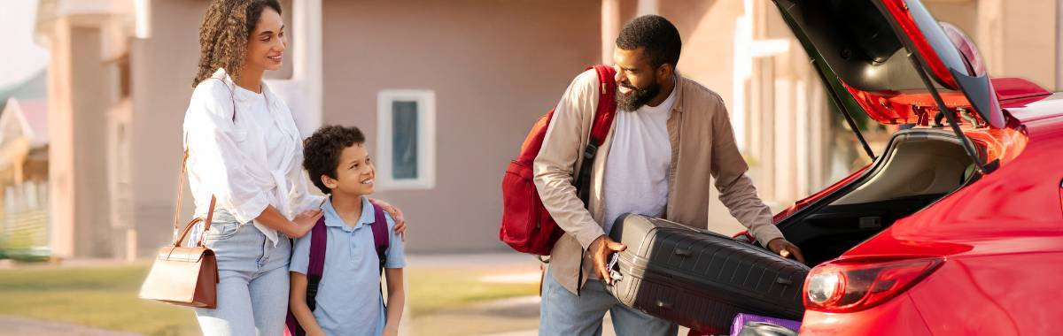 Father loading baggage into his car with his family