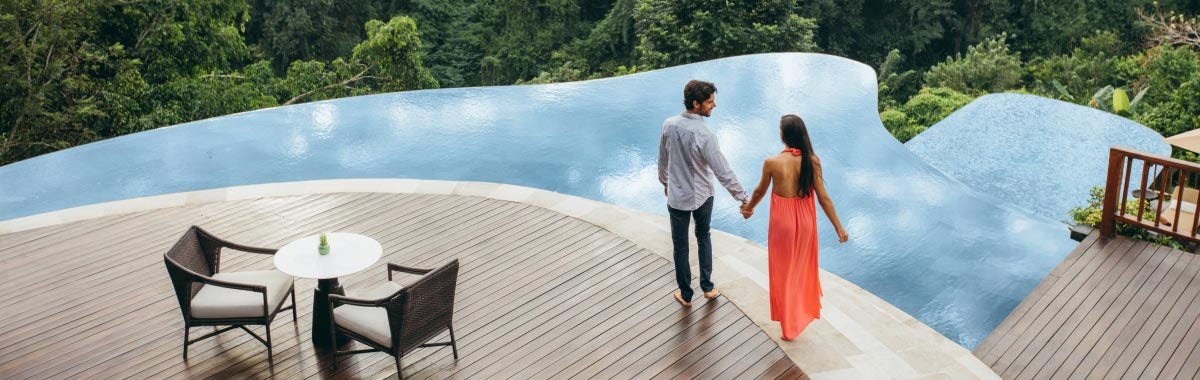two people on a luxurious deck overlooking a forest canopy at a high end resort