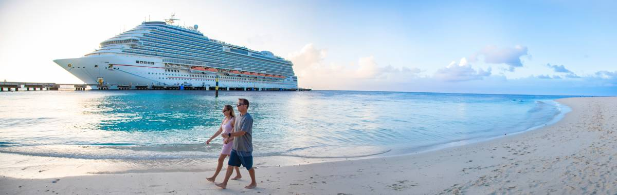 couple walking on a beach next to cruise ship