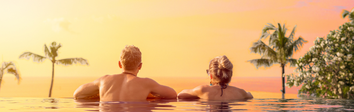 couple at the end of an infinity pool looking at the sunset