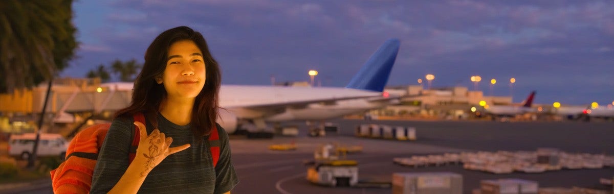 person giving a shaka sign and looking happy on an airport tarmac