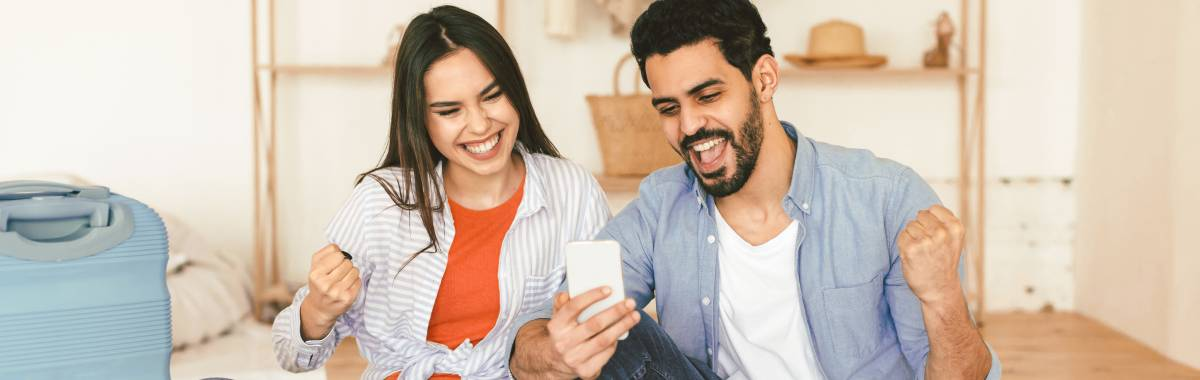 couple celebrating while looking at a phone