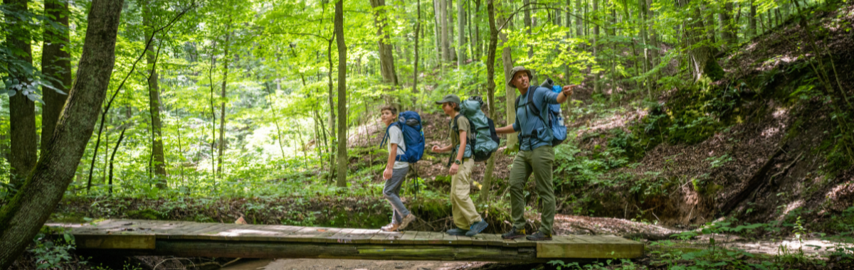 family hiking across a wooden bridge