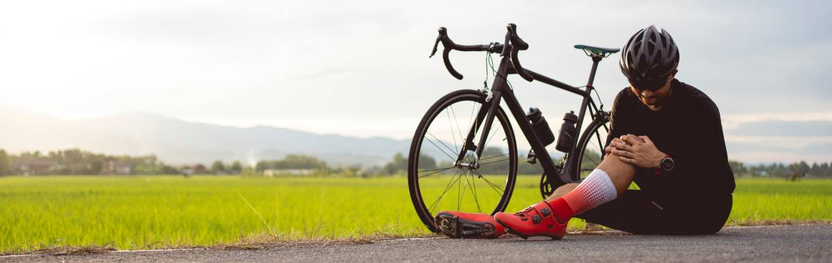 man holding his knee next to a bike