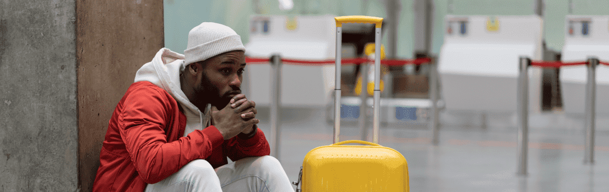 man sitting in the airport next to his luggage