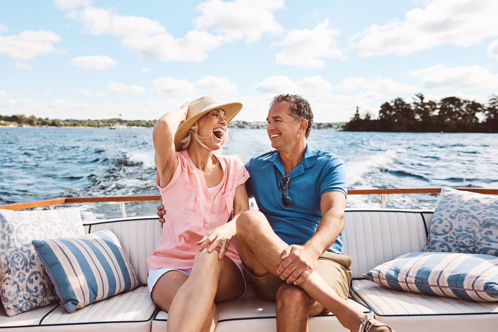 older couple laughing and having fun on the back of a boat in the water