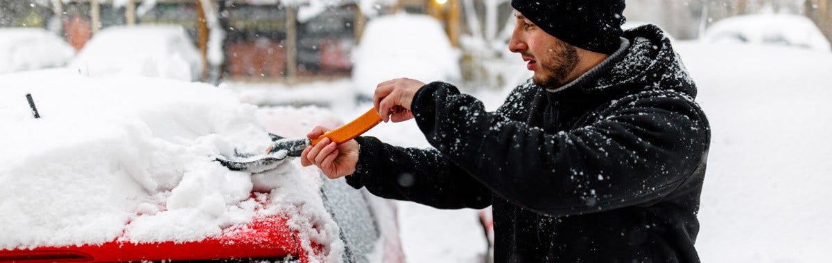 car in snow man with shovel