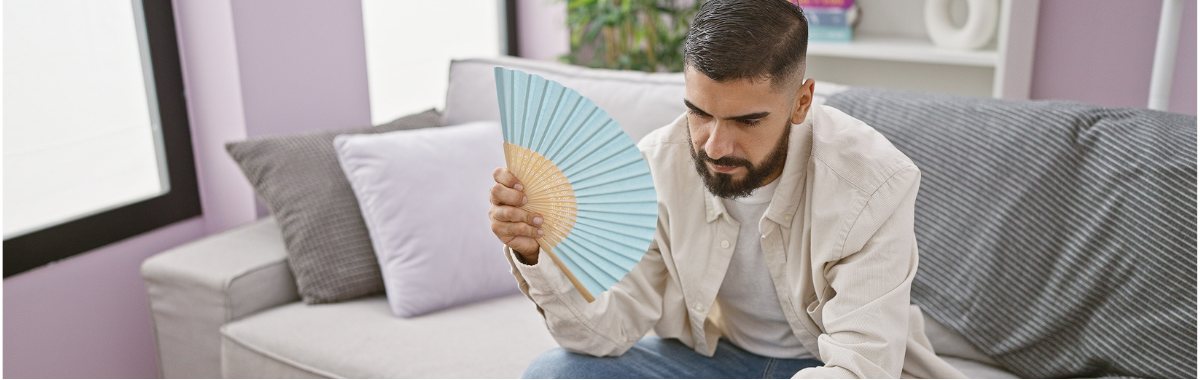 man fanning himself with a paper fan