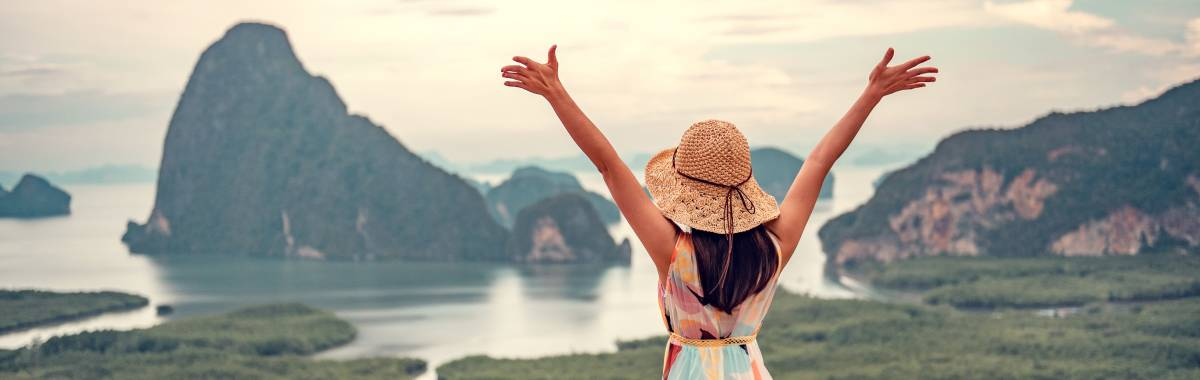 woman with her arms open looking as islands and mountains