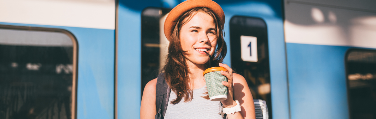 woman sipping coffee next to a train