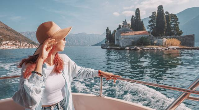 woman on boat looking back at a passing island