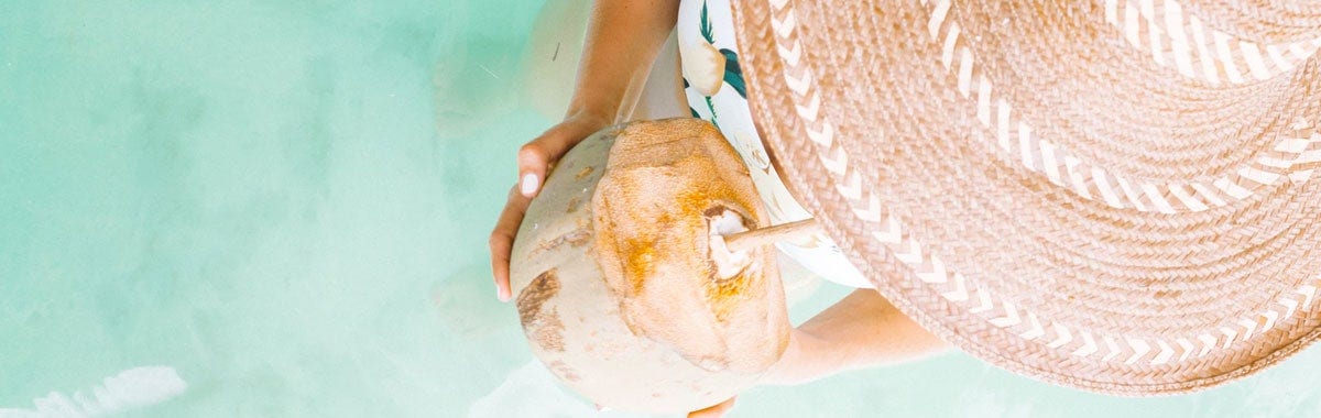 woman drinking from coconut in water on Caribbean vacation
