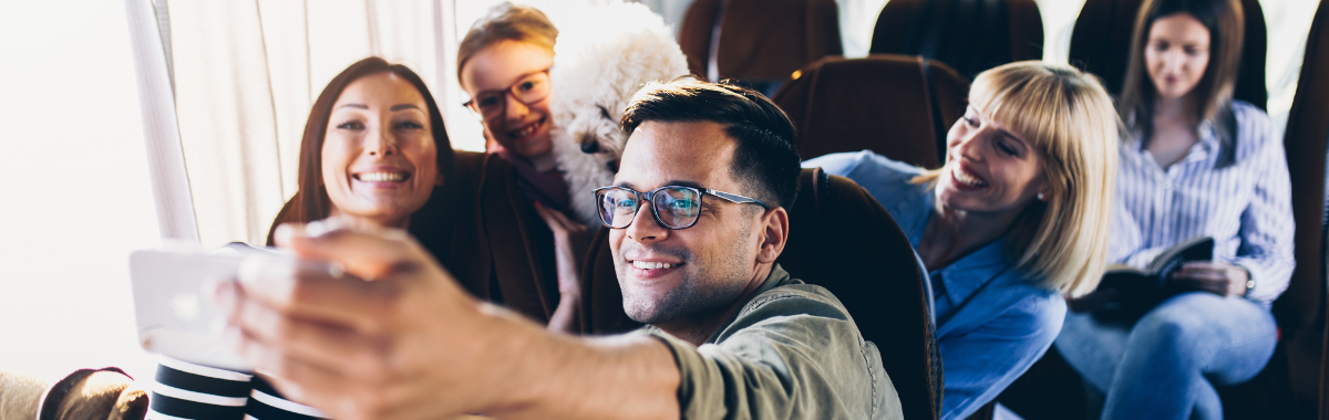 man taking group selfie on a bus