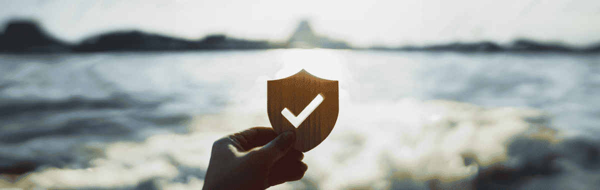 Checkmark inside a shield of a cutout infront of a reflecting pool