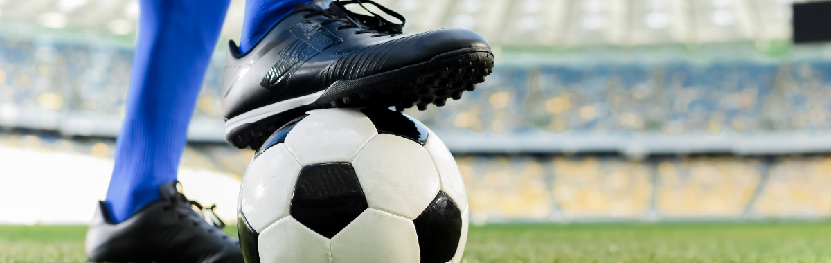 soccer ball on field with a player ready to kick