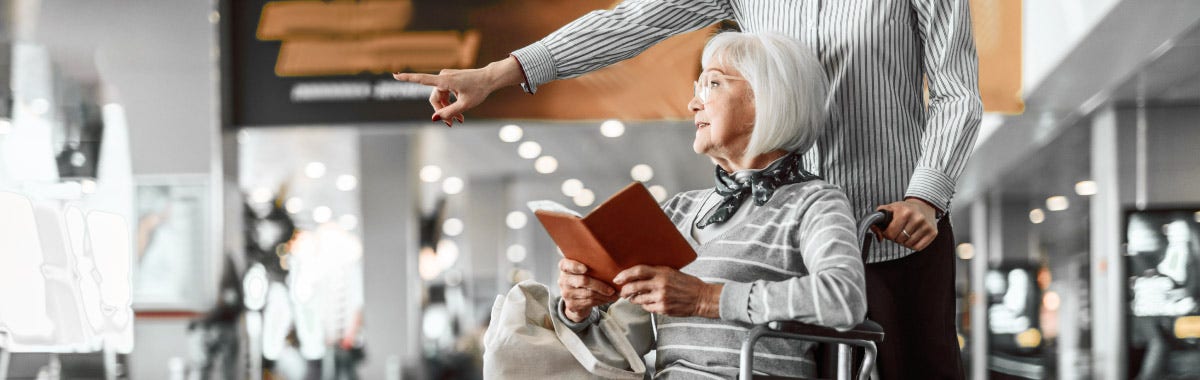 senior traveler reading a book in a wheel chair in an airport