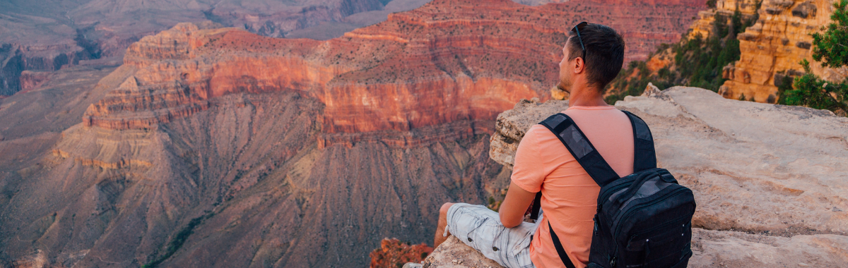 man sitting on the edge of the grand canyon