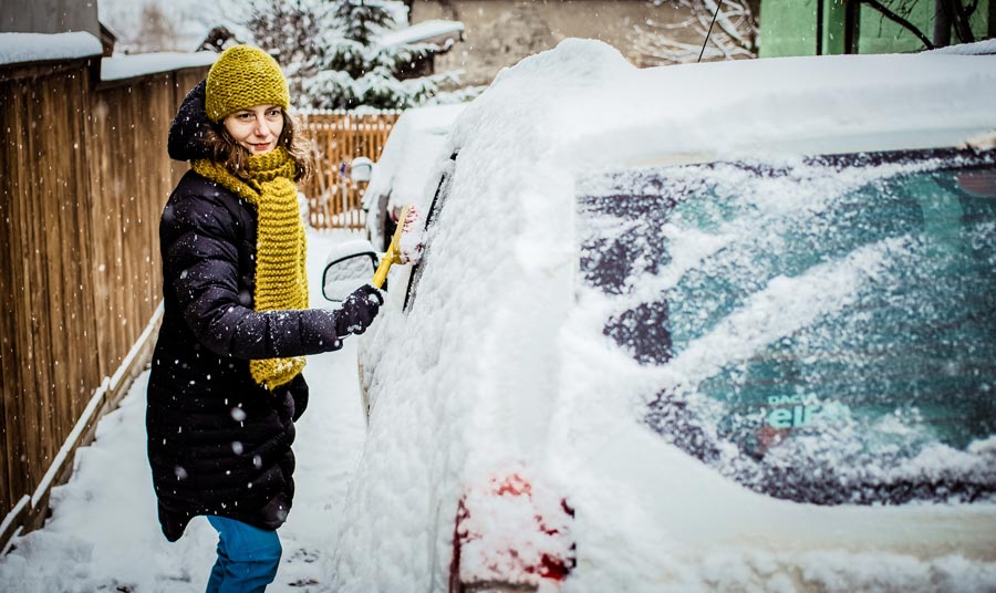 woman clearing off snow on her car