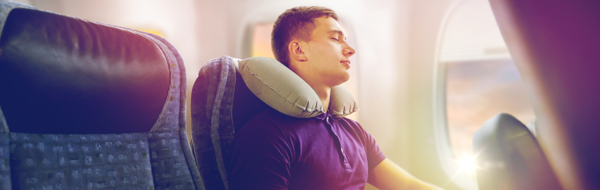 man sleeping on a plane with a neck pillow
