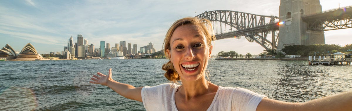 woman posing across the water from the Sydney opera house