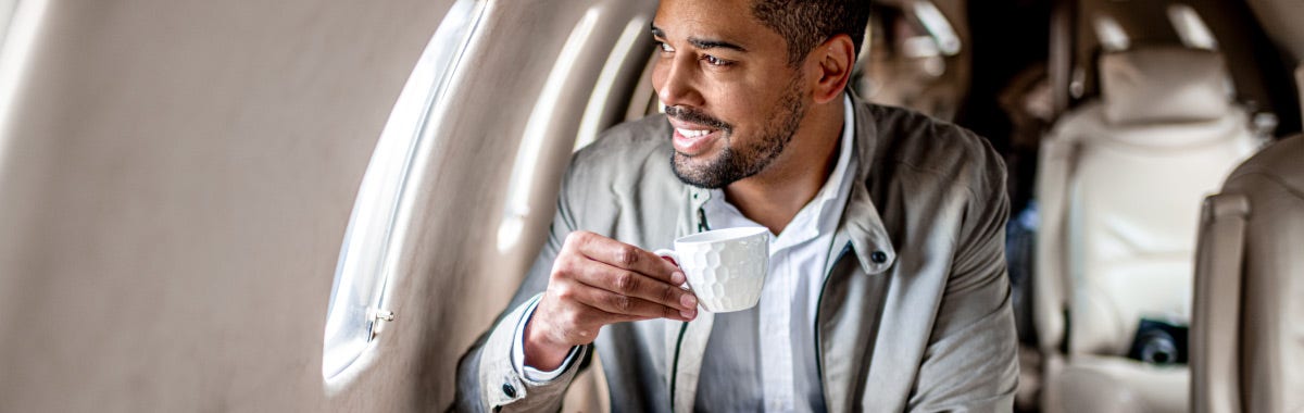 man drinking a coffee on a plane