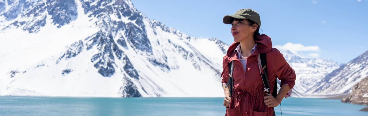 woman hiking in a red coat with an icy mountain in the background