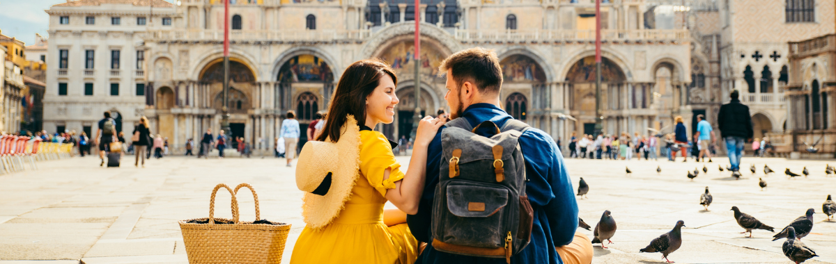 couple sitting together in a european courtyard with birds around them