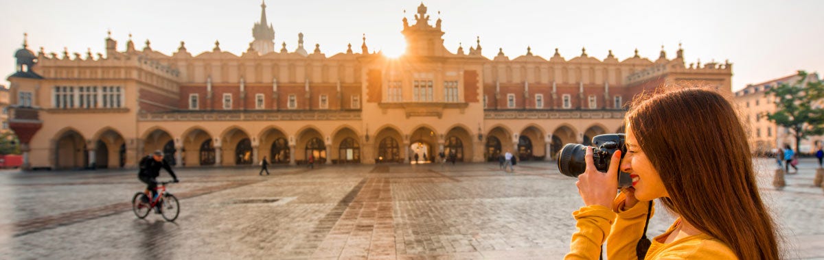 woman on a kayak with her arms out stretched over a emerald green lake
