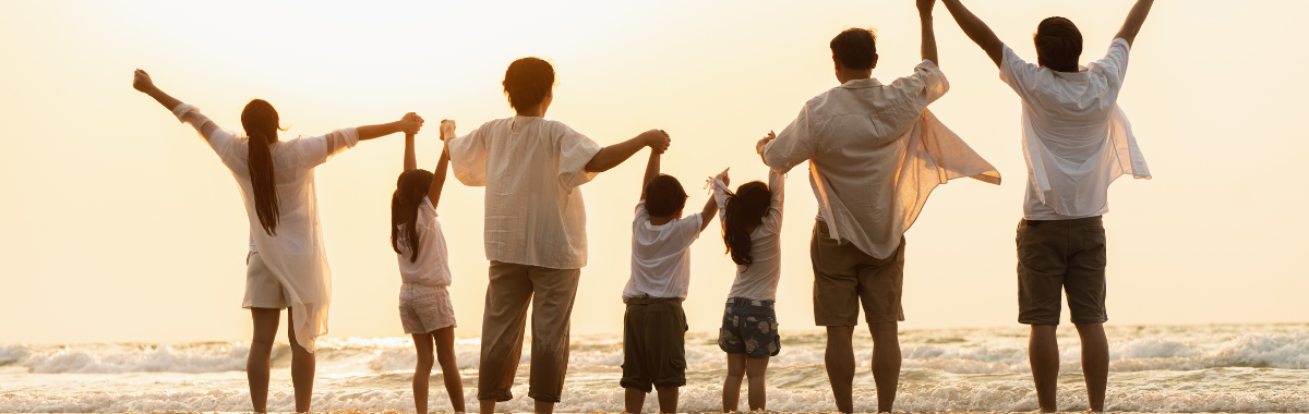 family standing on a beach with their hands up