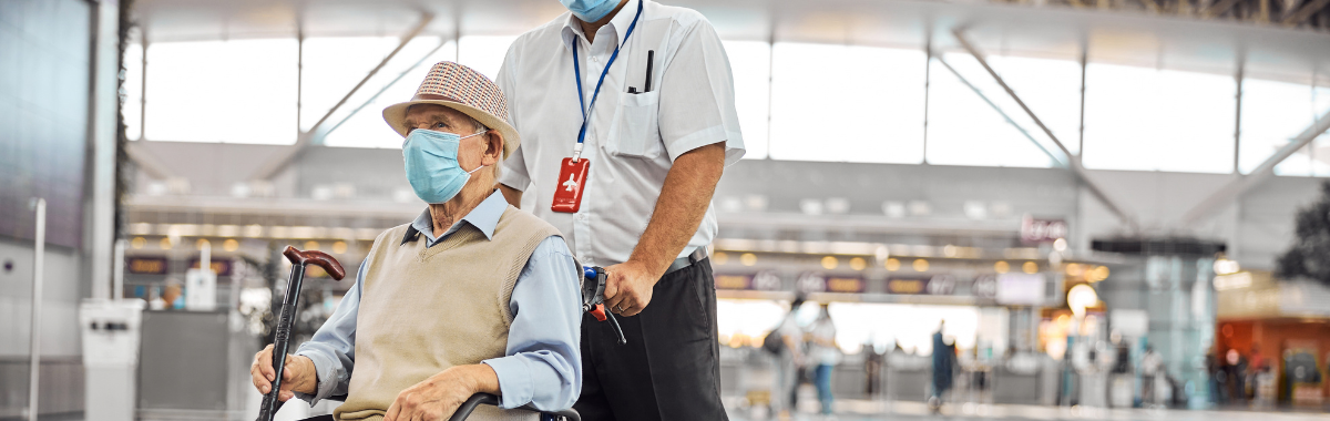 senior traveler in wheel chair being pushed in airport