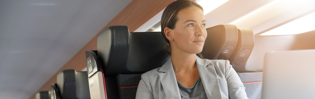 woman sitting in a business class seat with her laptop open on a plane