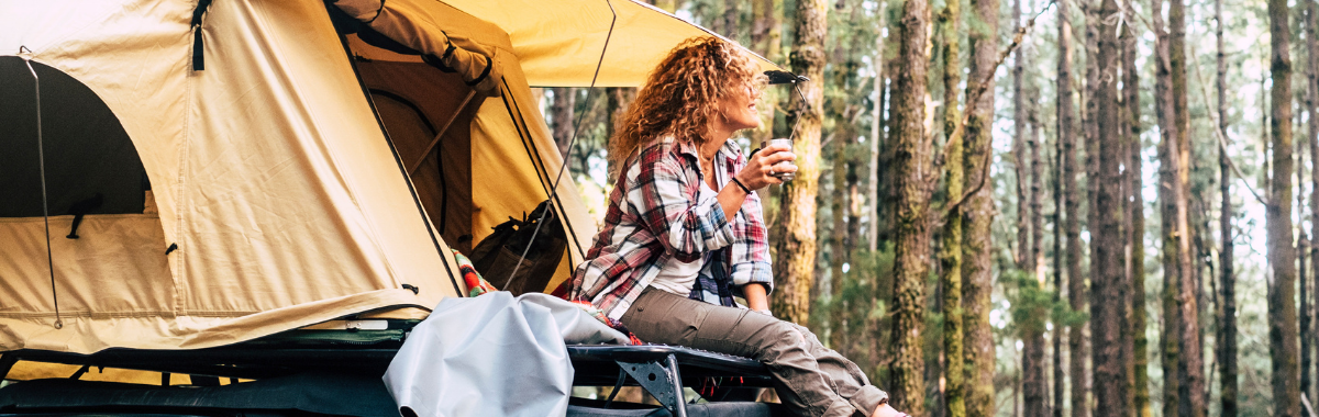 woman sitting atop her car with a tent on top