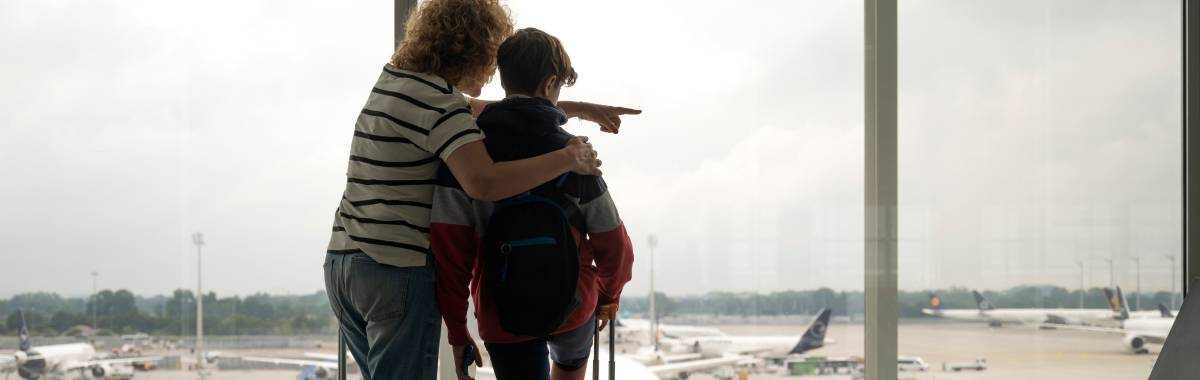 mom and son at the airport pointing at airplanes