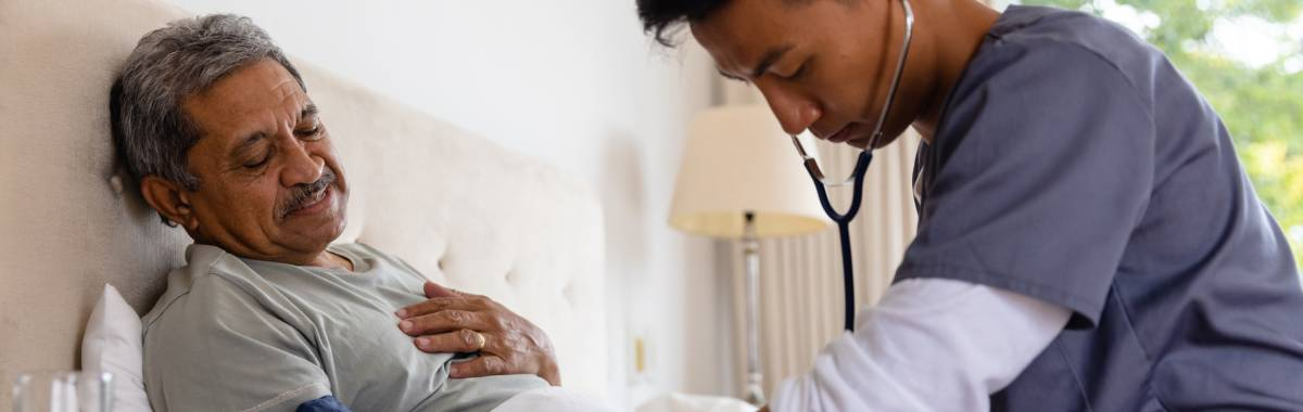 man in hospital bed with nurse helping him