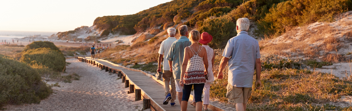 older travelers walking on a boardwalk to a beach