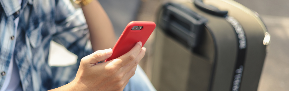 traveler on their phone next to a suitcase