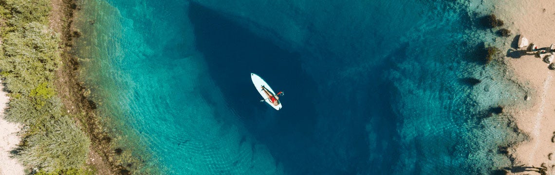person on a paddleboard in the middle of a crystal clear blue lake