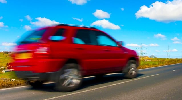 red car zooming past on a road trip