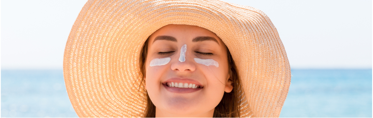 woman smiling wearing a sun hat with sunscreen on