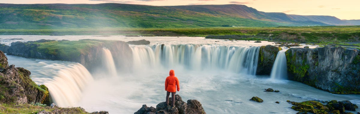 Person in red coat looking at big waterfall
