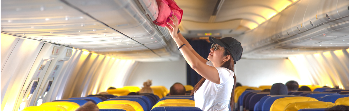 passenger storing bag in overhead compartment on airplane