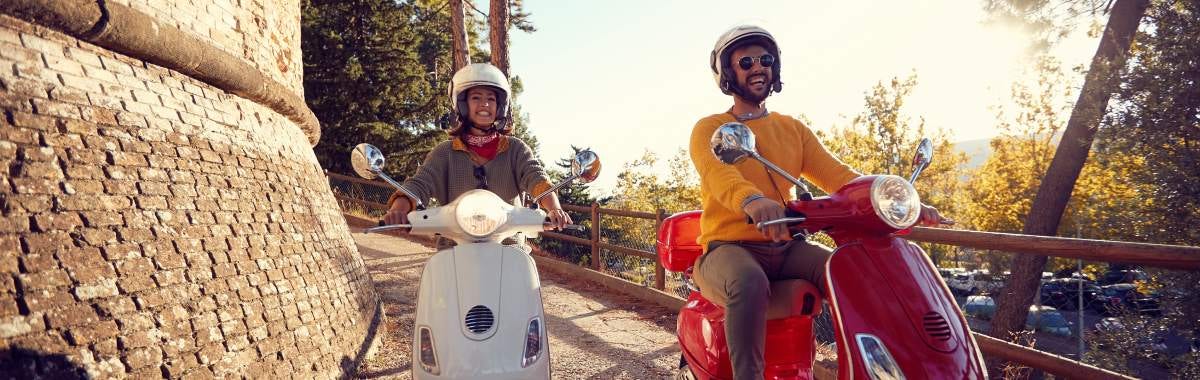 couple riding on mopeds on a road together at sunset