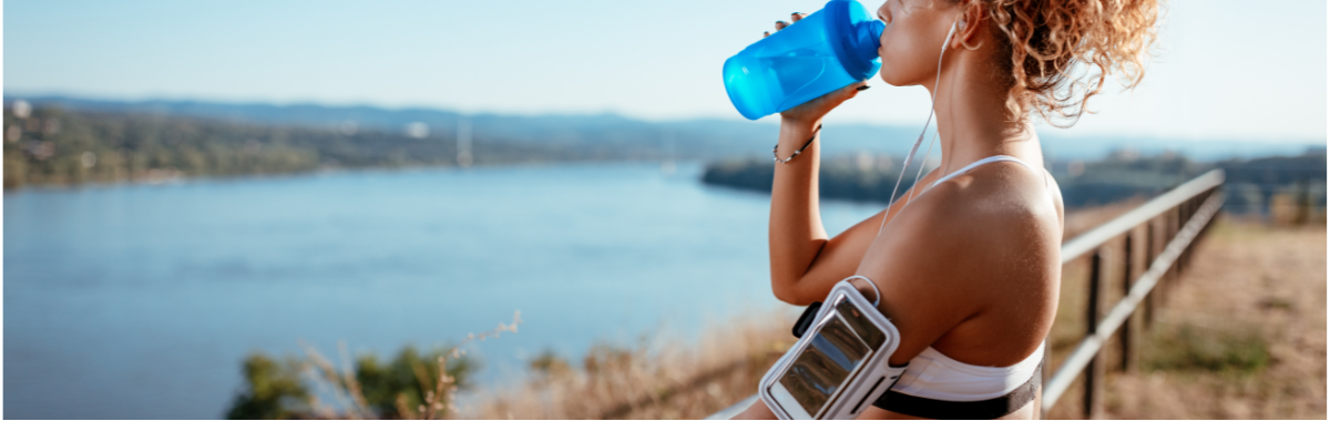 woman drinking water while on a run